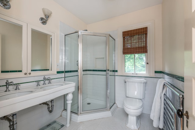 bathroom featuring tile patterned floors, a shower with door, toilet, and tile walls