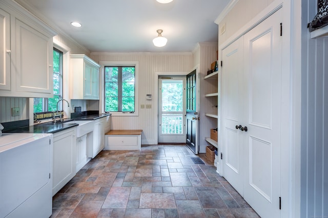 kitchen with ornamental molding, washer / dryer, white cabinetry, and sink