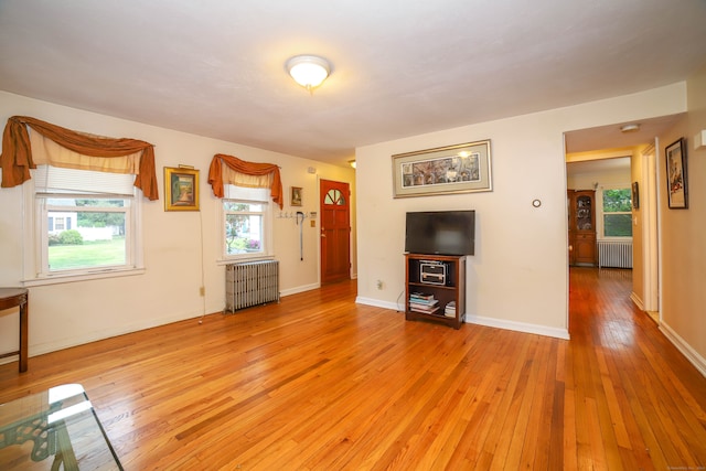 unfurnished living room with radiator heating unit and light wood-type flooring