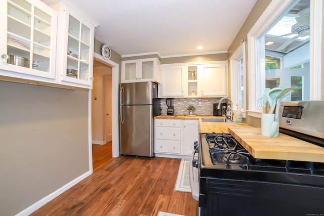 kitchen with white cabinets, stainless steel refrigerator, black gas stove, wood counters, and sink