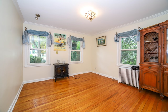 unfurnished room with light wood-type flooring, plenty of natural light, and radiator heating unit