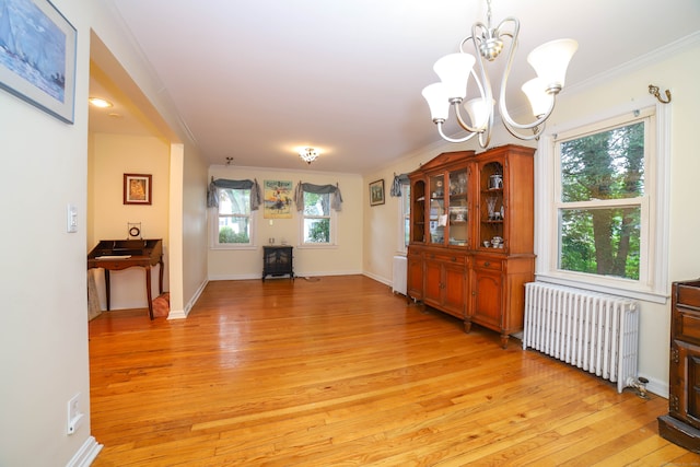 dining room featuring radiator heating unit, a notable chandelier, light hardwood / wood-style flooring, and ornamental molding