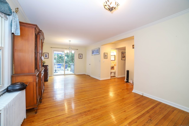 interior space with light hardwood / wood-style floors, ornamental molding, a chandelier, and radiator heating unit