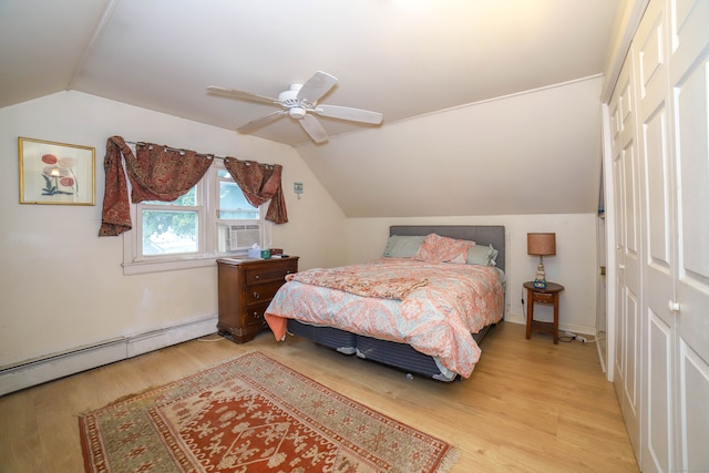 bedroom featuring vaulted ceiling, a closet, ceiling fan, light hardwood / wood-style flooring, and a baseboard heating unit