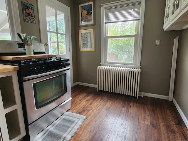 kitchen with radiator heating unit, gas stove, butcher block counters, and dark hardwood / wood-style flooring