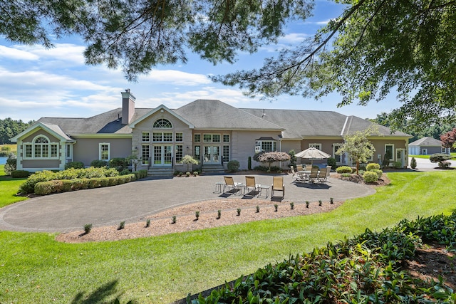 back of property with a patio, a lawn, and french doors