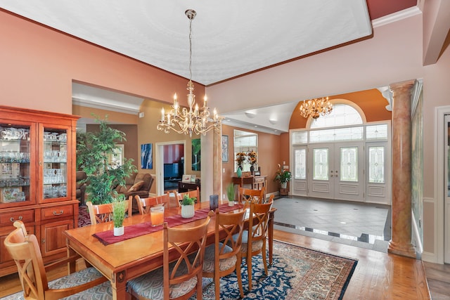 dining space featuring ornamental molding, wood-type flooring, decorative columns, an inviting chandelier, and vaulted ceiling