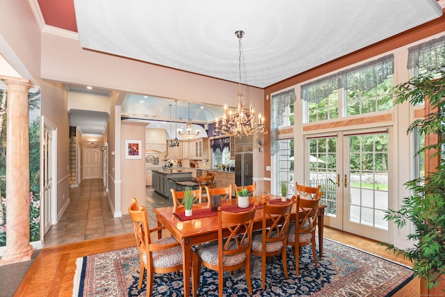 dining room with ornate columns, an inviting chandelier, french doors, and plenty of natural light