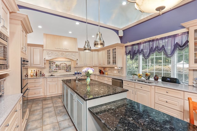 kitchen featuring tasteful backsplash, pendant lighting, a center island, dark stone counters, and sink