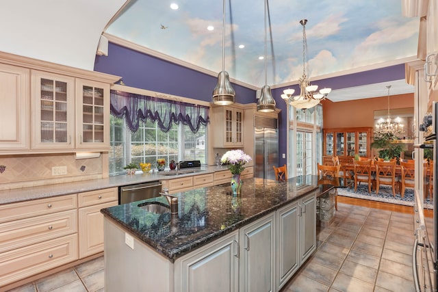 kitchen featuring pendant lighting, dark stone counters, a kitchen island with sink, an inviting chandelier, and stainless steel appliances