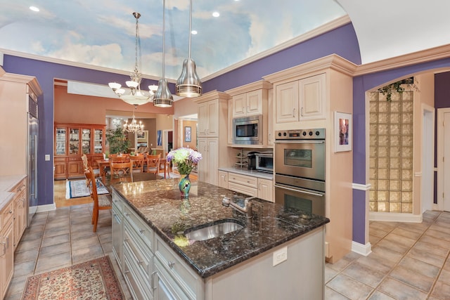 kitchen with sink, a kitchen island with sink, decorative light fixtures, stainless steel appliances, and a notable chandelier