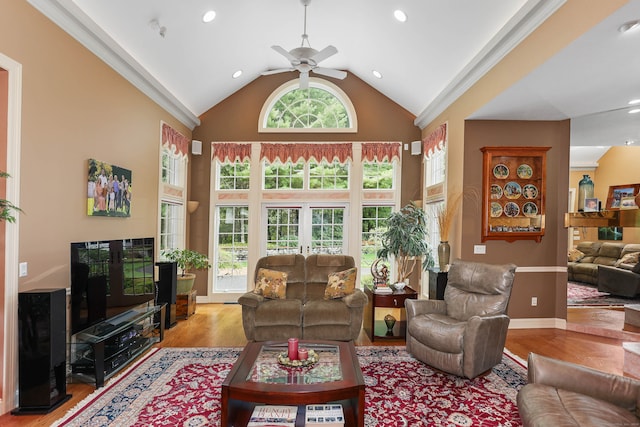 living room with light wood-type flooring, ornamental molding, ceiling fan, and high vaulted ceiling