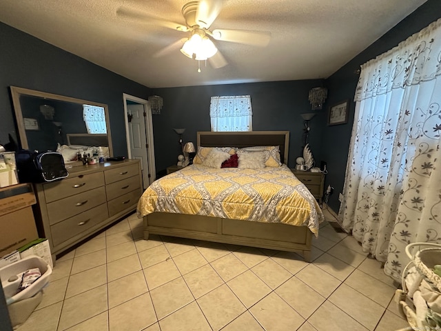 tiled bedroom featuring multiple windows, ceiling fan, and a textured ceiling