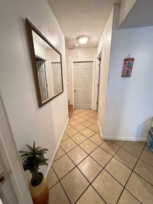 hallway with light tile patterned floors and a textured ceiling