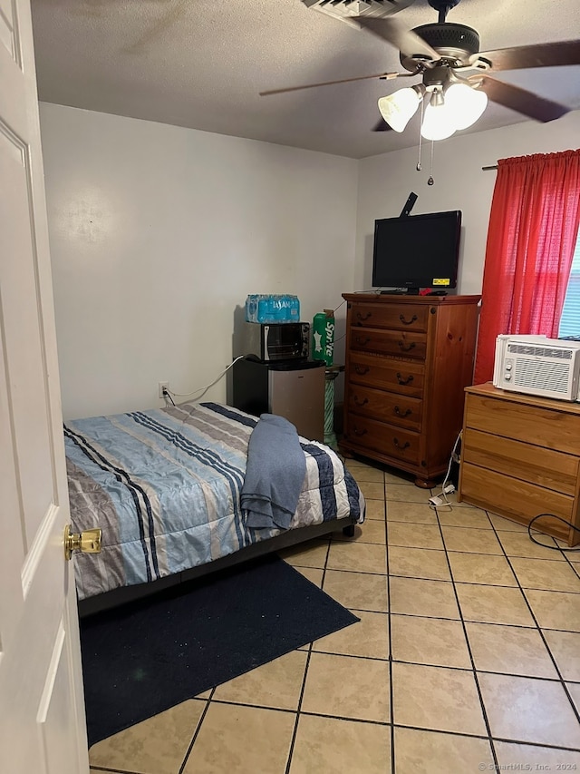 bedroom featuring a textured ceiling, cooling unit, light tile patterned floors, and ceiling fan