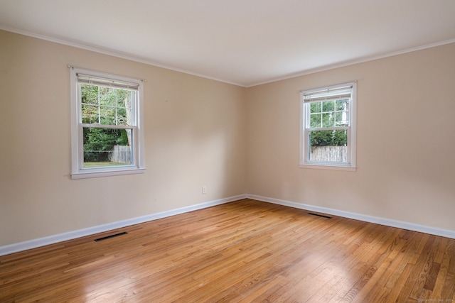 unfurnished room featuring a healthy amount of sunlight, ornamental molding, and light hardwood / wood-style flooring