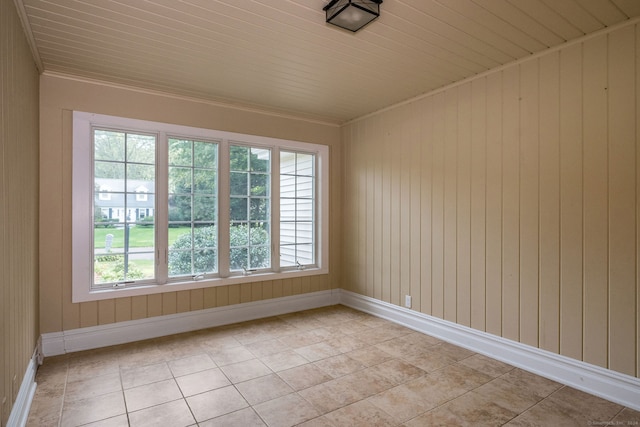 tiled empty room featuring wood walls, wooden ceiling, and plenty of natural light