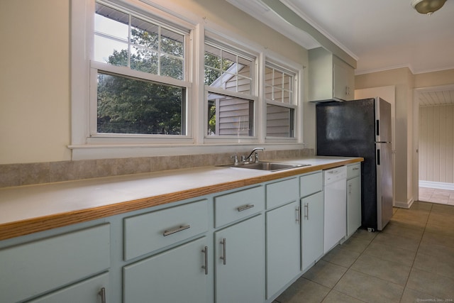 kitchen with sink, white dishwasher, white cabinetry, crown molding, and light tile patterned floors