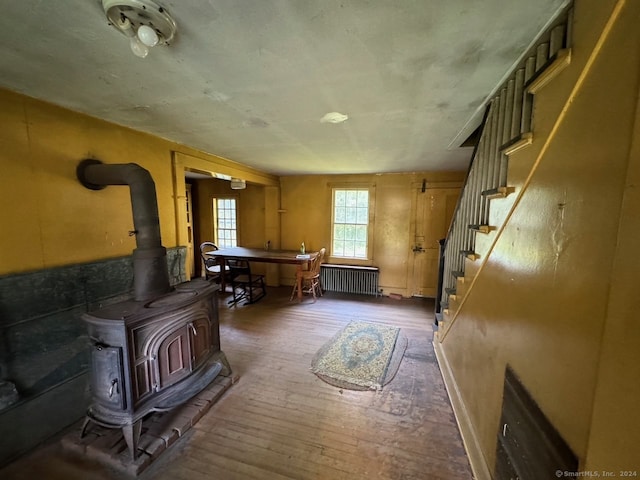 misc room featuring wood-type flooring, a wood stove, and radiator