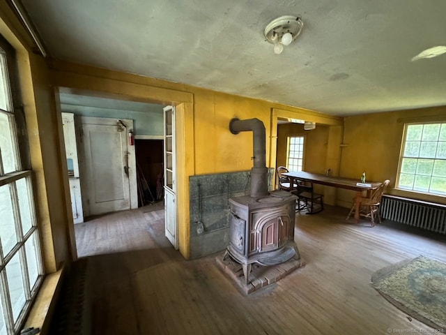 misc room featuring hardwood / wood-style flooring, a wood stove, and radiator heating unit