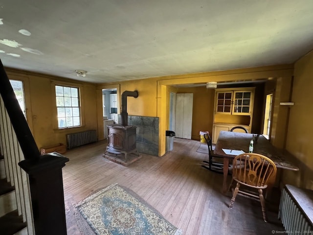 living room with wood-type flooring, a wood stove, and radiator