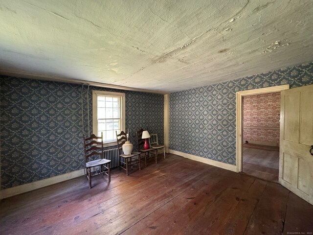 sitting room with radiator heating unit and dark hardwood / wood-style floors