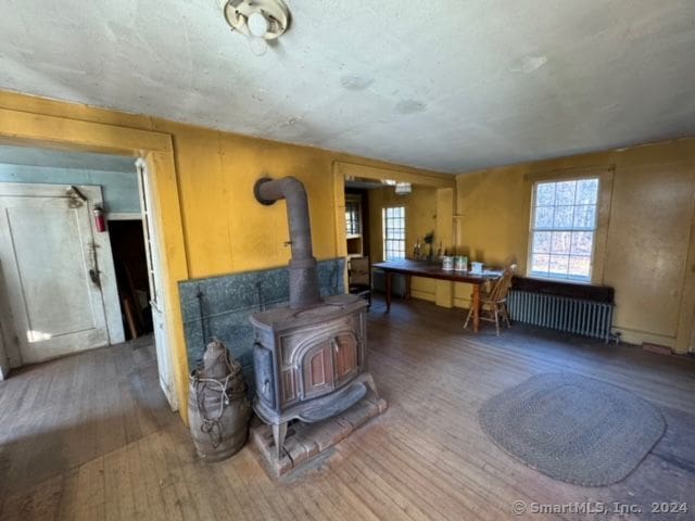 misc room with radiator heating unit, hardwood / wood-style flooring, and a wood stove