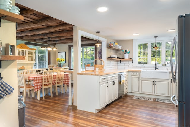 kitchen with white cabinetry, appliances with stainless steel finishes, hardwood / wood-style floors, and hanging light fixtures