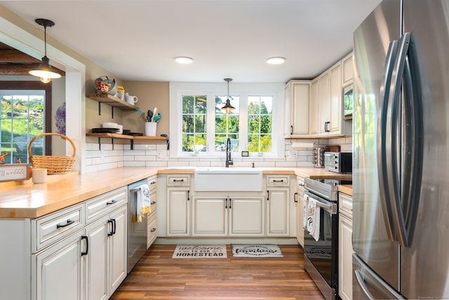 kitchen with sink, appliances with stainless steel finishes, decorative light fixtures, and hardwood / wood-style flooring