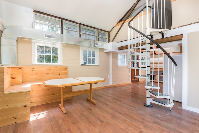 living area featuring a high ceiling, hardwood / wood-style flooring, and wooden walls