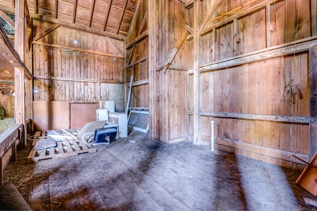 misc room featuring lofted ceiling and wood walls