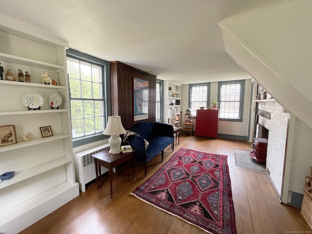 interior space featuring radiator, built in features, a brick fireplace, and hardwood / wood-style flooring