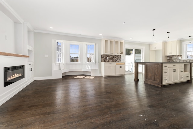 unfurnished living room featuring ornamental molding, plenty of natural light, and dark hardwood / wood-style floors