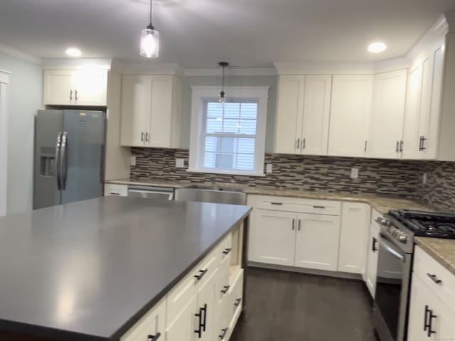 kitchen featuring white cabinets, ornamental molding, decorative light fixtures, appliances with stainless steel finishes, and decorative backsplash