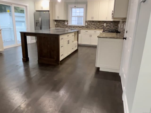 kitchen with backsplash, white cabinetry, stainless steel refrigerator with ice dispenser, a center island, and dark hardwood / wood-style flooring