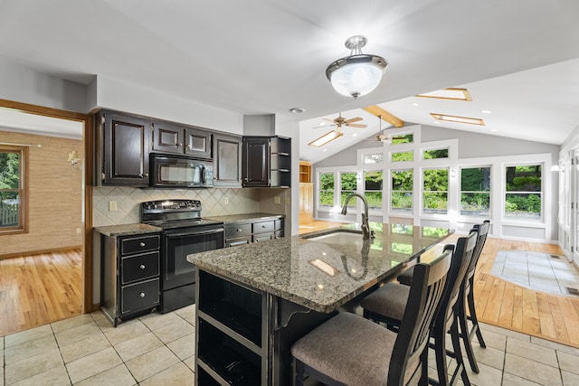 kitchen featuring sink, black appliances, vaulted ceiling, and light hardwood / wood-style floors