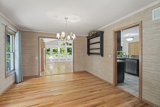 unfurnished dining area featuring light hardwood / wood-style floors, crown molding, sink, and an inviting chandelier