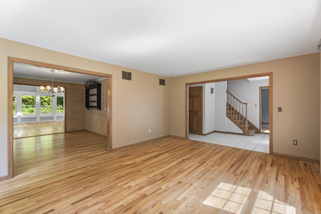 unfurnished room with a notable chandelier and light wood-type flooring