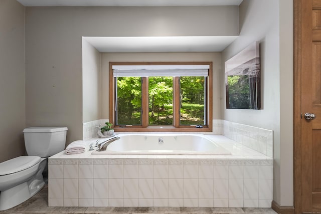 bathroom with tile patterned floors, a relaxing tiled tub, and toilet