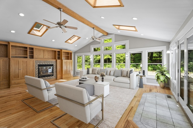 living room with light wood-type flooring, a skylight, ceiling fan, high vaulted ceiling, and beamed ceiling