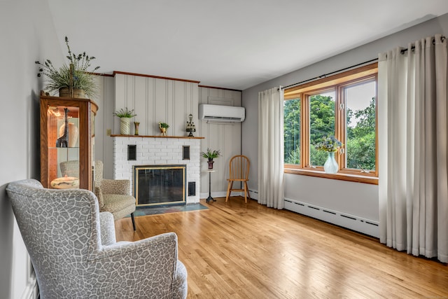 living room featuring light wood-type flooring, a fireplace, a baseboard heating unit, and a wall unit AC