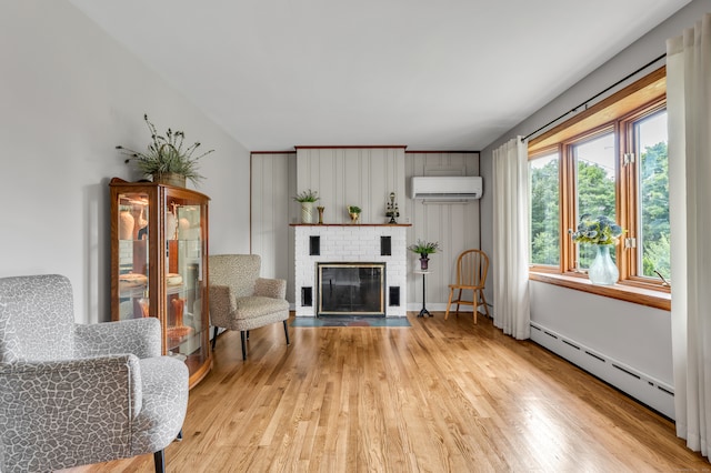 living room with light hardwood / wood-style floors, a fireplace, baseboard heating, and a wall mounted air conditioner