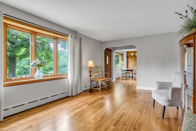 living area with light hardwood / wood-style floors and a baseboard heating unit