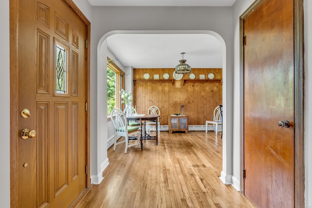 entrance foyer featuring a baseboard heating unit, wood walls, and hardwood / wood-style floors