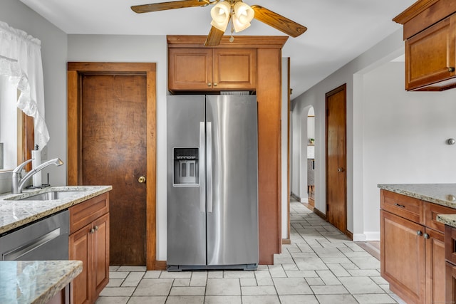 kitchen with ceiling fan, light tile patterned floors, sink, appliances with stainless steel finishes, and light stone countertops