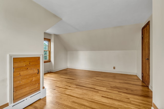 additional living space featuring light hardwood / wood-style flooring, vaulted ceiling, and baseboard heating