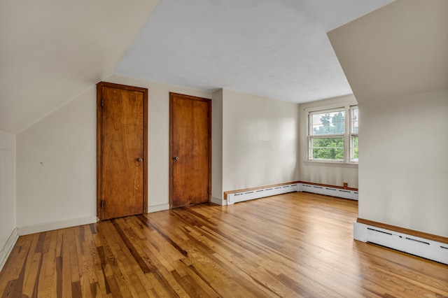 bonus room with light hardwood / wood-style flooring, a baseboard heating unit, and lofted ceiling