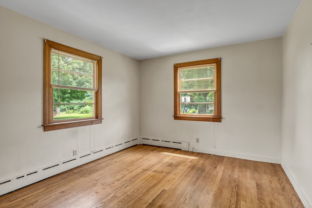 unfurnished room with a baseboard radiator and light wood-type flooring