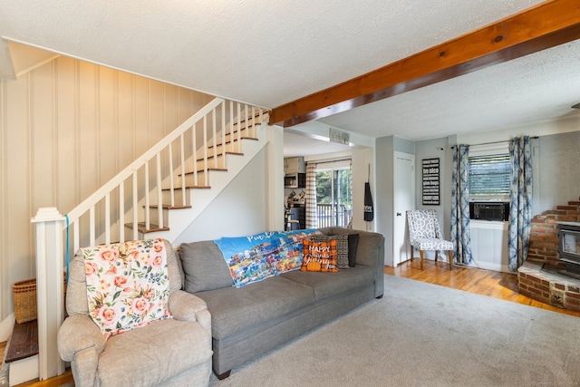 living room featuring a textured ceiling, beamed ceiling, a wood stove, a fireplace, and hardwood / wood-style floors