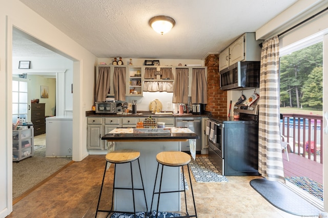 kitchen with light colored carpet, a textured ceiling, appliances with stainless steel finishes, and a kitchen island